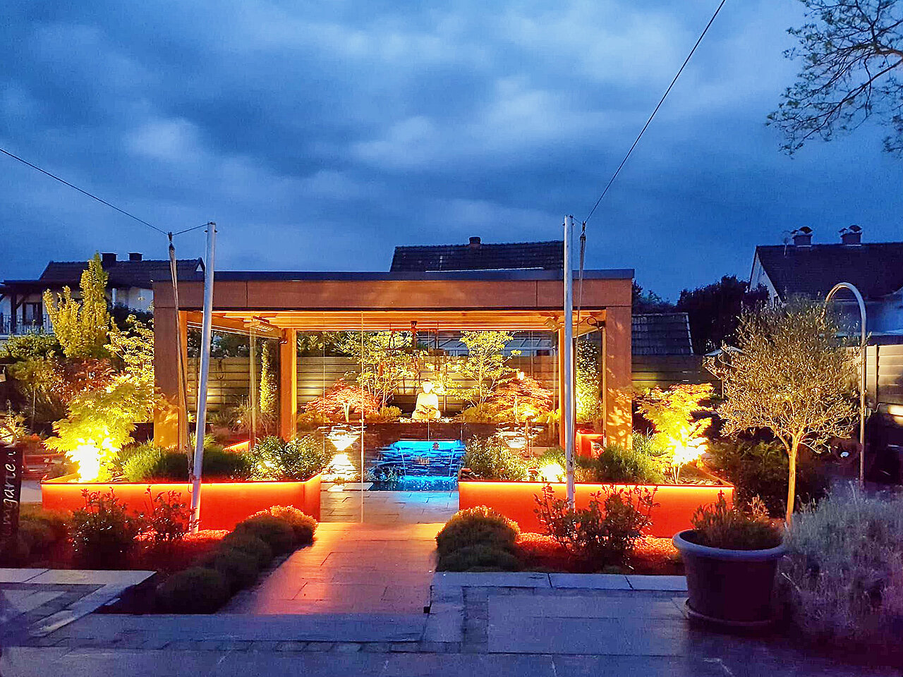 Moderne Gartenanlage mit Wasserbecken und Natursteinplatten, in Abendstimmung